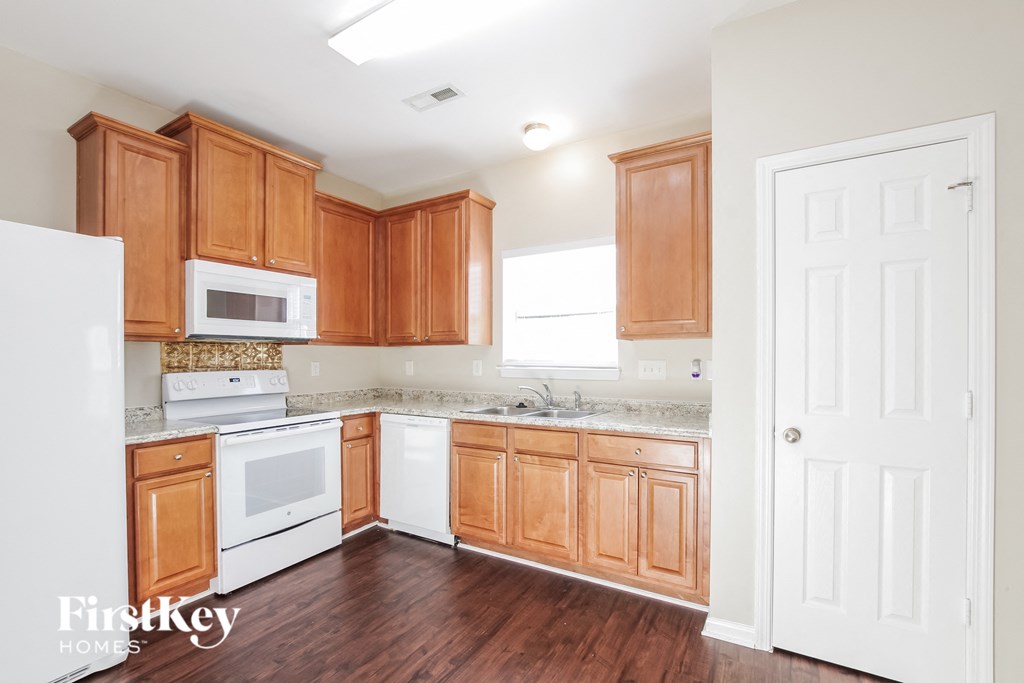 a kitchen with wooden cabinets and white appliances and wooden floors