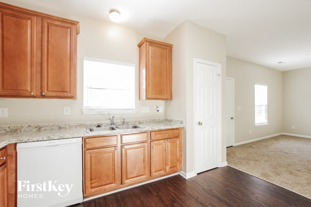 a kitchen with wooden cabinets and a sink and a door to the living room