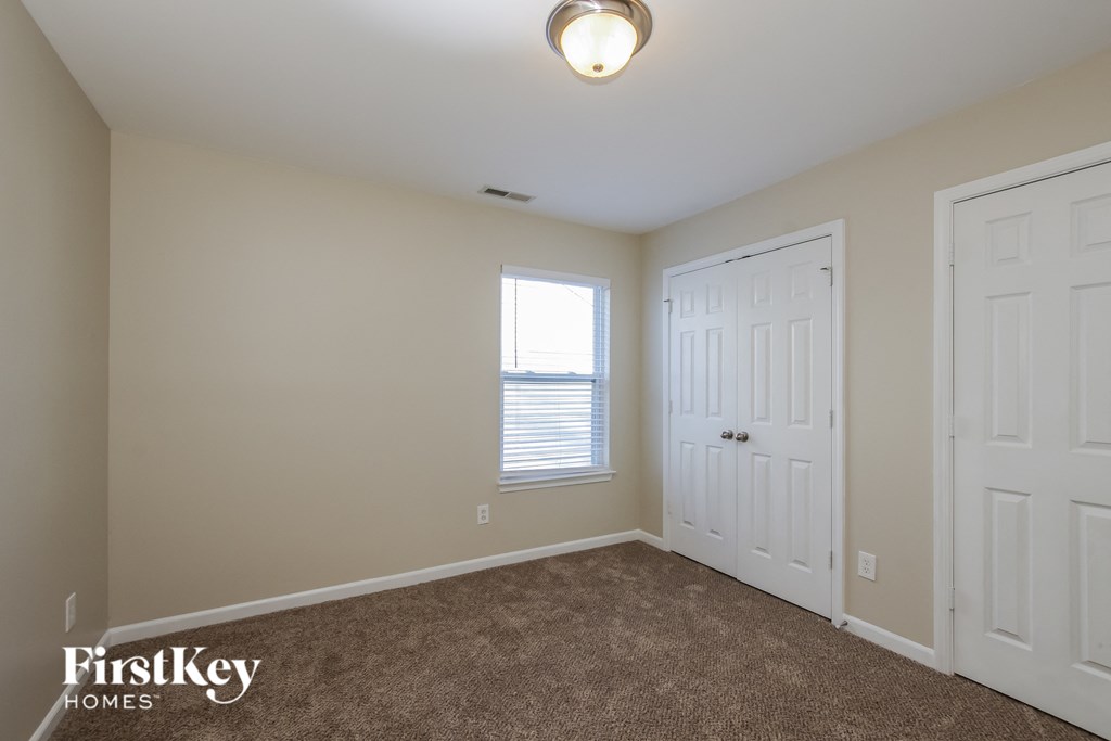 a bedroom with a carpeted floor and two doors and a window
