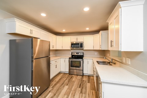 A modern kitchen with wooden floors and stainless steel appliances.