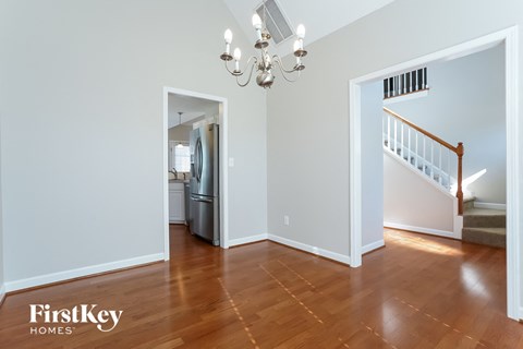 a living room with hardwood floors and a staircase and a kitchen with a refrigerator