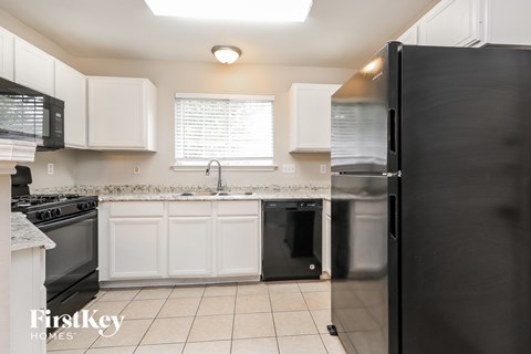 A kitchen with white cabinets and black appliances.