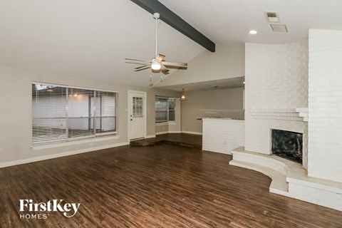 A spacious living room with a fireplace and a ceiling fan.