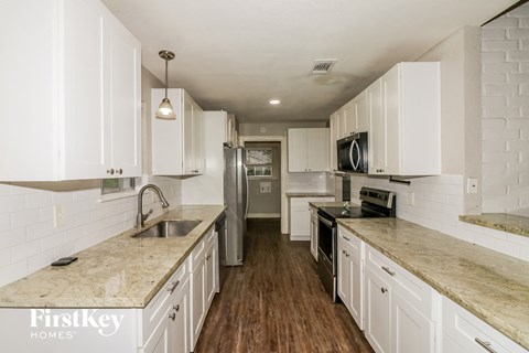 A kitchen with white cabinets and a wooden floor.