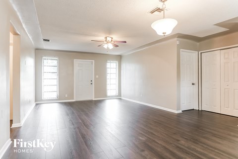 A spacious room with wooden floors and white walls.