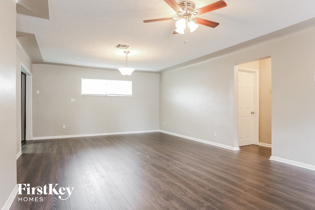 A spacious room with a ceiling fan and wooden flooring.