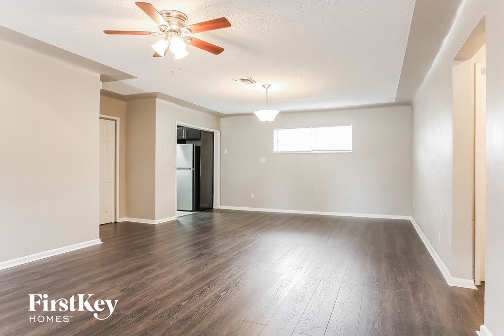 A spacious room with a ceiling fan and wooden flooring.