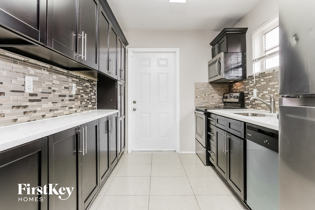 A kitchen with black cabinets and a white door.