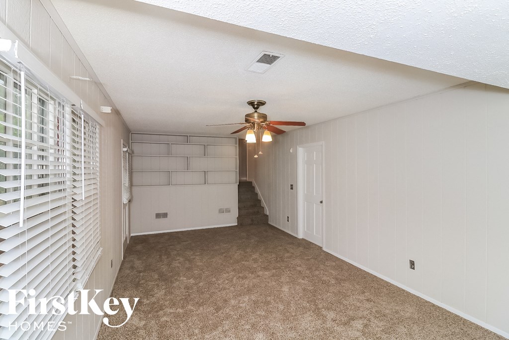 a hallway with white shutters and a ceiling fan and a staircase
