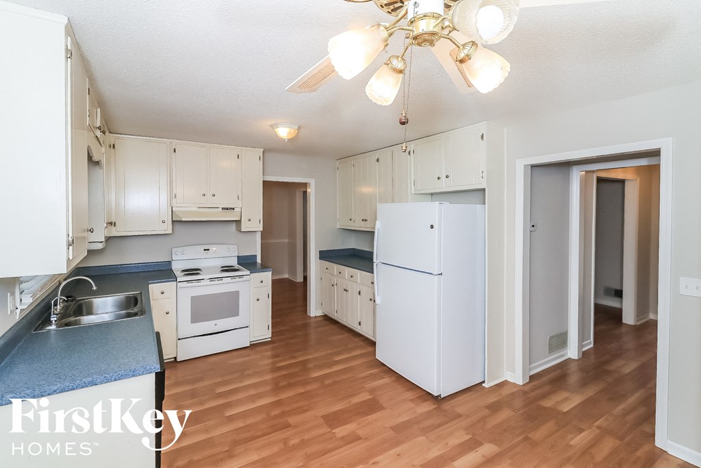a kitchen with white appliances and white cabinets and a wood floor