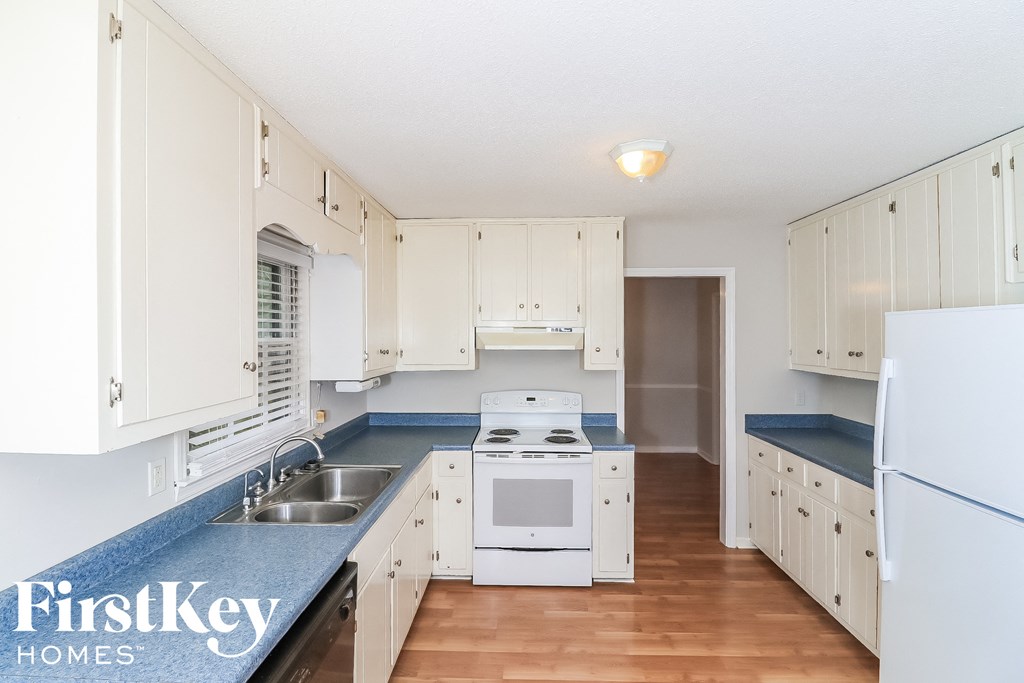 a white kitchen with blue counter tops and white appliances