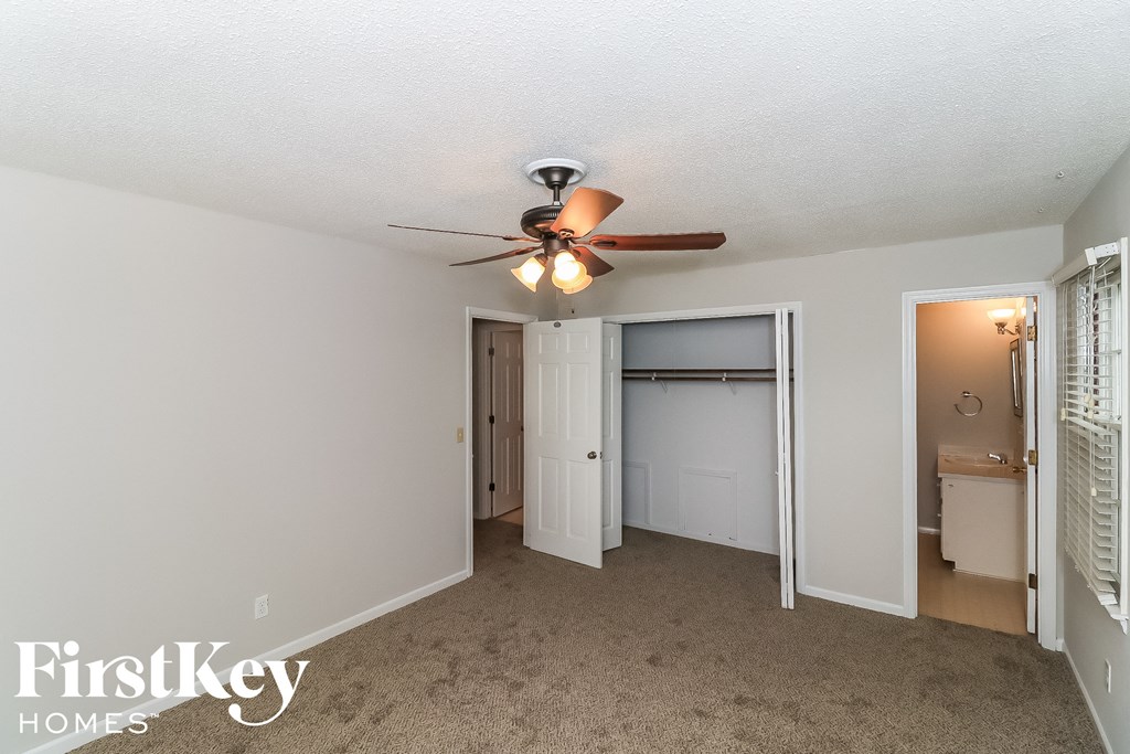 a bedroom with a ceiling fan and a door to a closet
