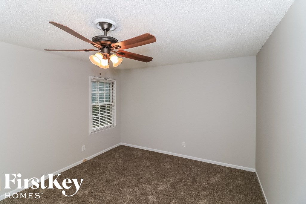 a bedroom with a ceiling fan and a carpet