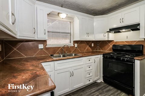 A kitchen with white cabinets and a black stove top oven.