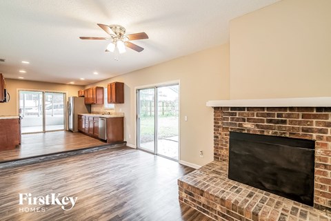 a living room with a fireplace and a kitchen with a sliding glass door