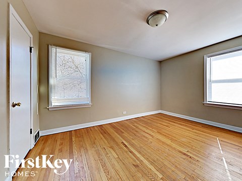 an empty living room with hardwood floors and two windows