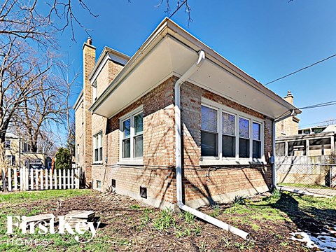 the front of a brick house with a white fence