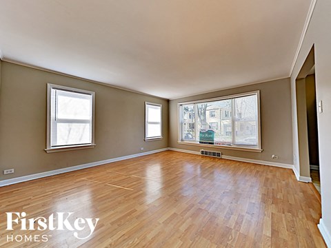 an empty living room with wood floors and a large window