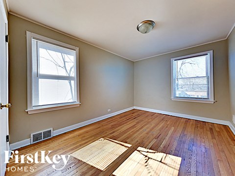 an empty living room with hardwood floors and two windows