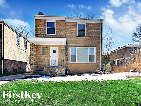the front of a brick house with snow on the yard