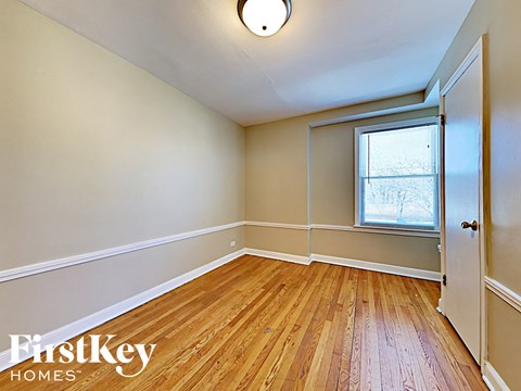 an empty bedroom with wood flooring and a window