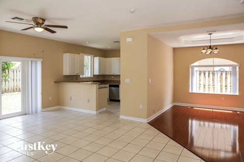 A spacious room with a kitchen area and a dining table.