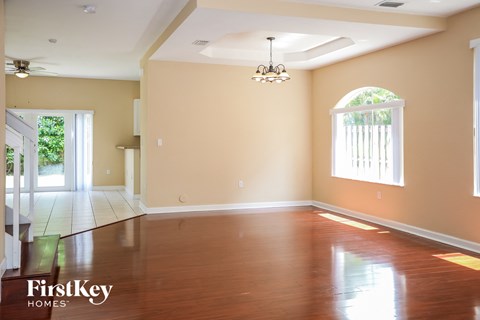 A spacious room with wooden floors and a chandelier.