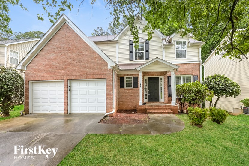A brick house with a white garage door is for sale.