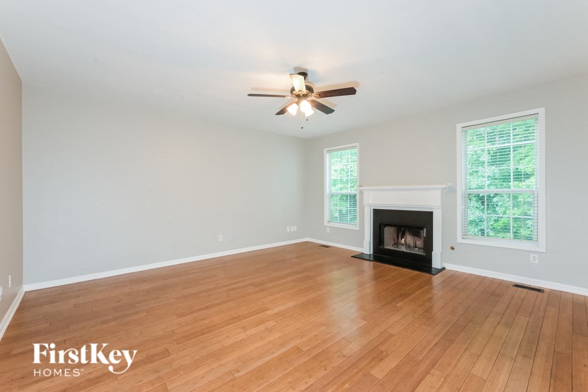 A spacious room with a fireplace and a ceiling fan.