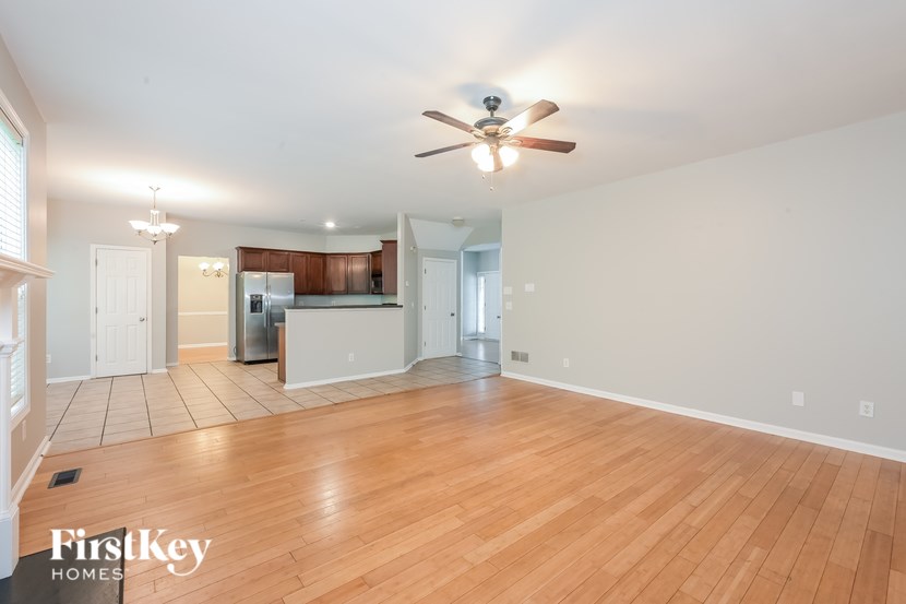 A spacious living room with a ceiling fan and hardwood floors.