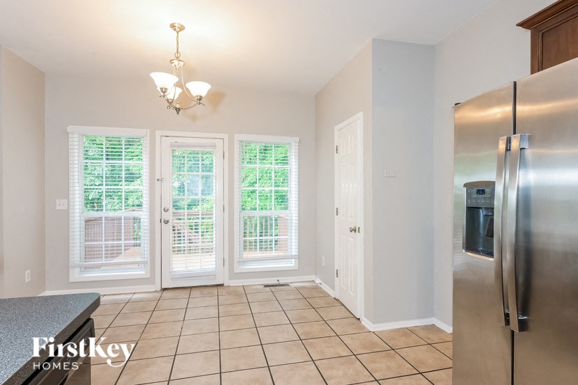A kitchen with a refrigerator, a table, and a chandelier.
