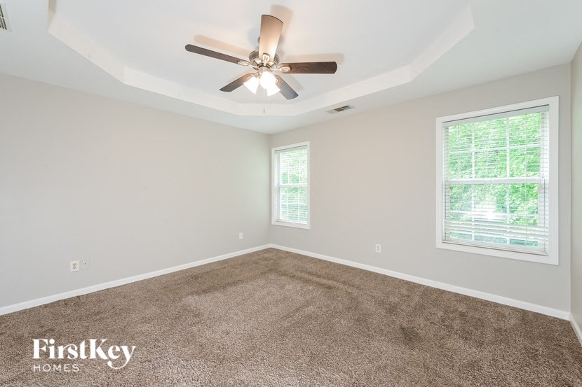 A room with a carpeted floor and a ceiling fan.