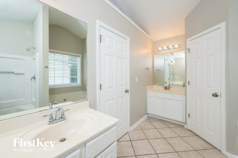 A white bathroom with a sink, mirror, and lighted mirror.
