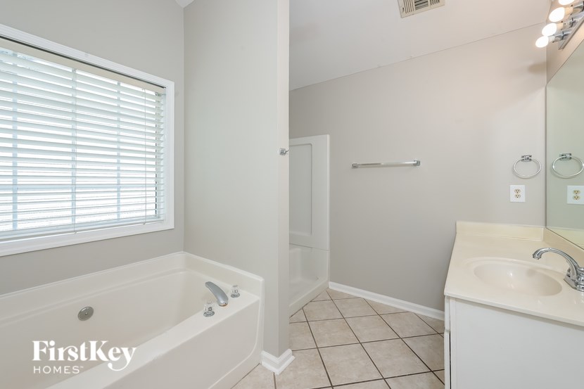 A white bathroom with a tub, sink and mirror.