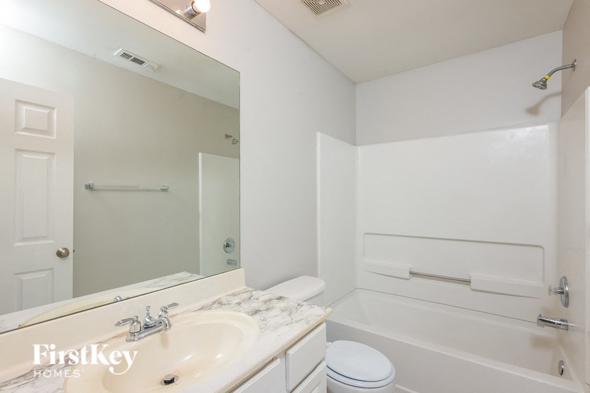 A white bathroom with a marble sink and a white toilet.