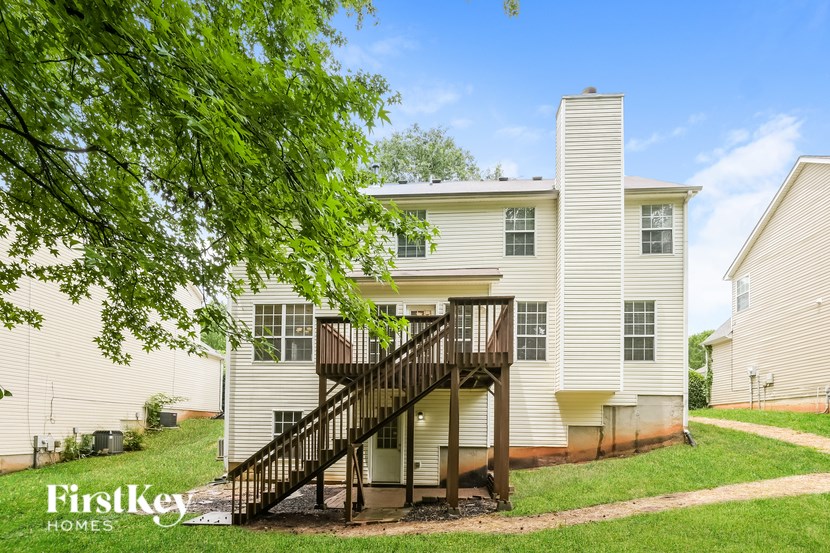 A white two-story house with a balcony and a staircase leading to the front door.