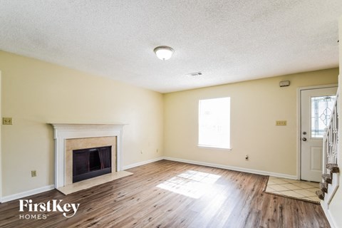 A spacious room with a fireplace and wooden floors.