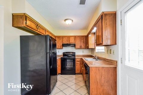 A kitchen with wooden cabinets and a black refrigerator.