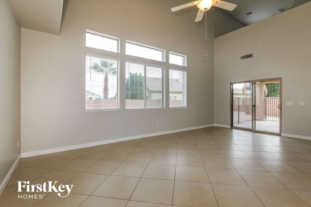 an empty living room with windows and a ceiling fan