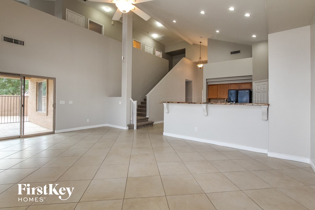 an empty living room with a kitchen and a staircase