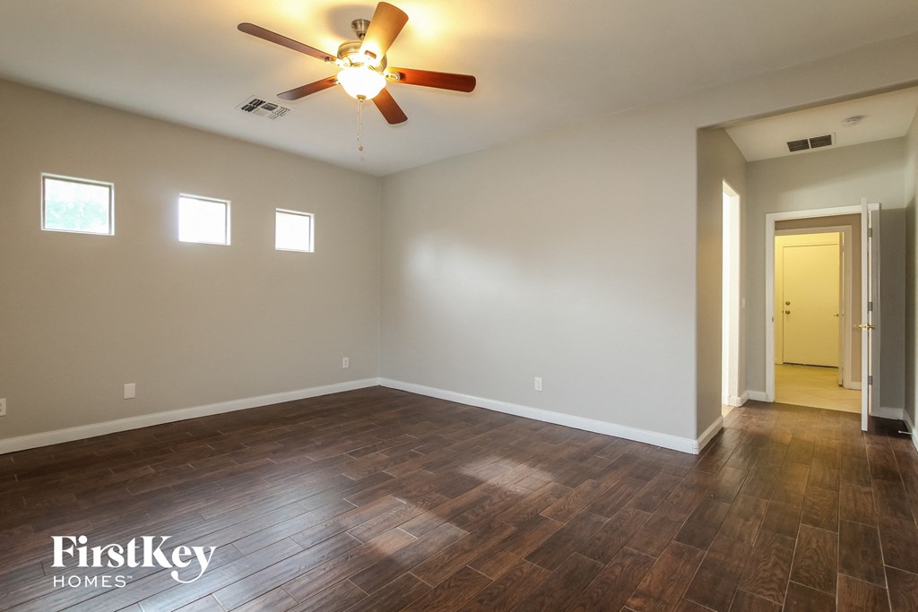 a empty living room with wood floors and a ceiling fan