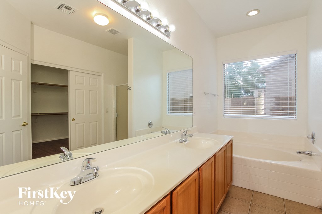 a bathroom with two sinks and a tub and a large mirror