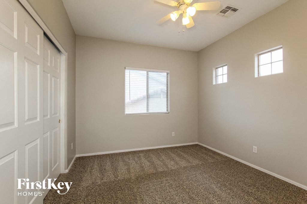 the living room of an empty house with carpet and a ceiling fan