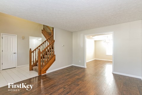 A spacious room with a wooden staircase and white walls.