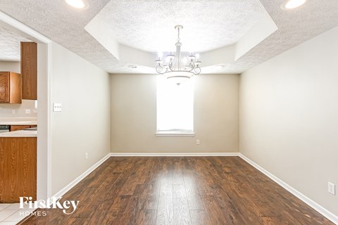 A large empty room with wooden floors and a chandelier.