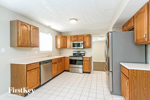 A kitchen with wooden cabinets and a white tile floor.