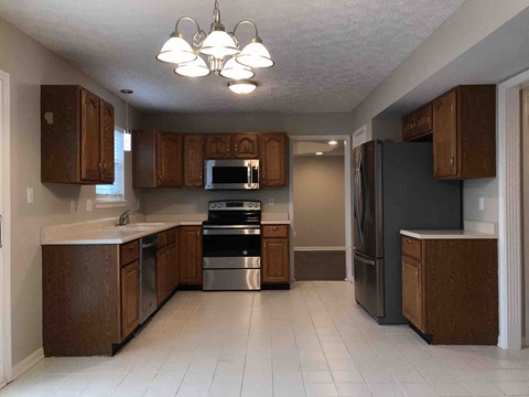 A kitchen with brown cabinets and a black refrigerator.