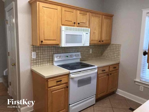 A kitchen with wooden cabinets and a white stove top oven.