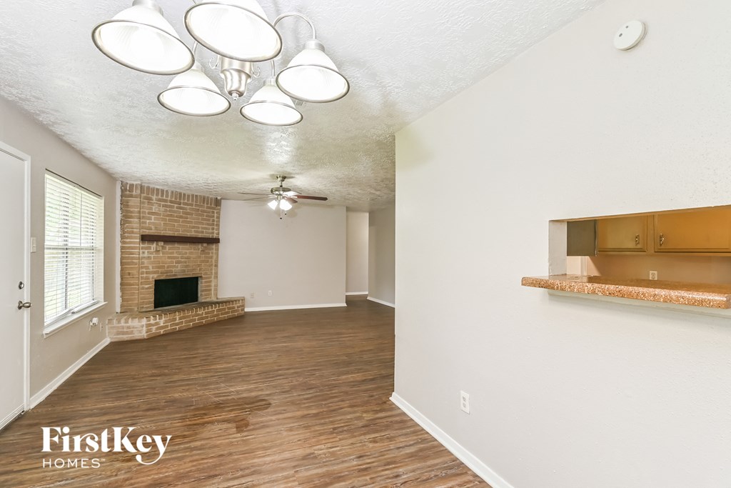 an empty living room with a fireplace and a ceiling fan