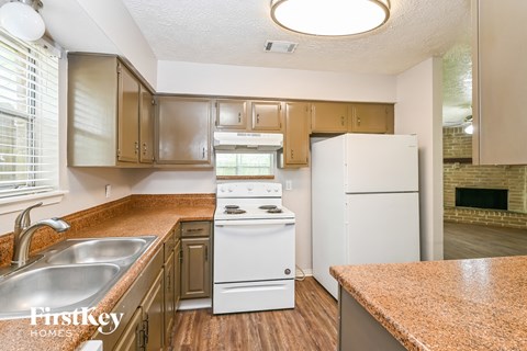 an updated kitchen with white appliances and granite counter tops